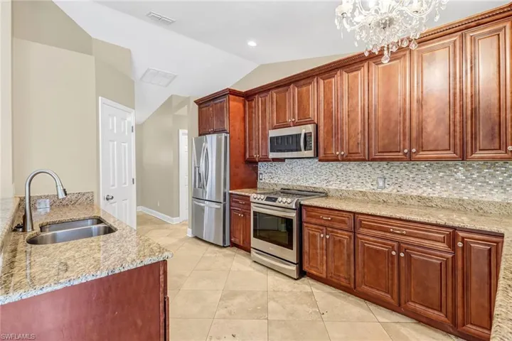 Kitchen featuring a notable chandelier, sink, backsplash, and appliances with stainless steel finishes