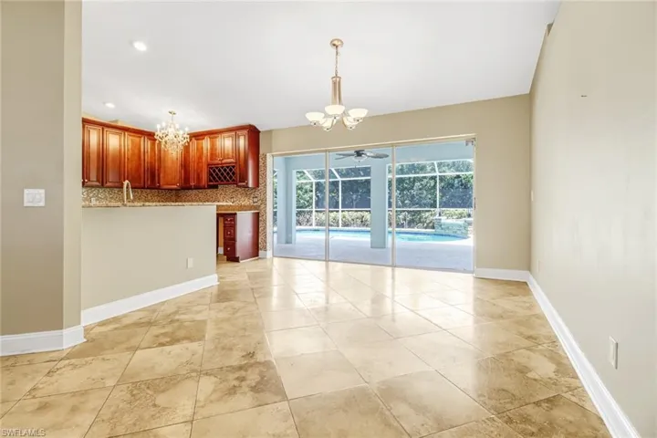 Kitchen with ceiling fan with notable chandelier, tasteful backsplash, light tile floors, and pendant lighting