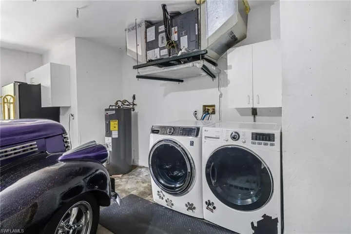 Clothes washing area featuring washer and clothes dryer, cabinets, washer hookup, and water heater