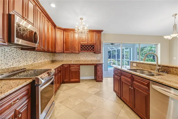 Kitchen with appliances with stainless steel finishes, sink, an inviting chandelier, and pendant lighting