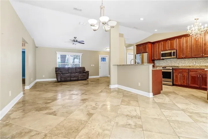 Kitchen with light tile floors, tasteful backsplash, ceiling fan with notable chandelier, and stainless steel appliances