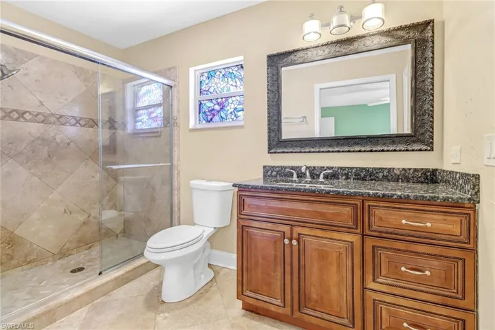 Bathroom with vanity, toilet, tile floors, and a shower with door
