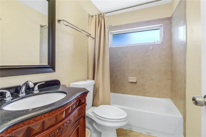 Full bathroom with tile flooring, toilet, oversized vanity, and shower / bath combo with shower curtain