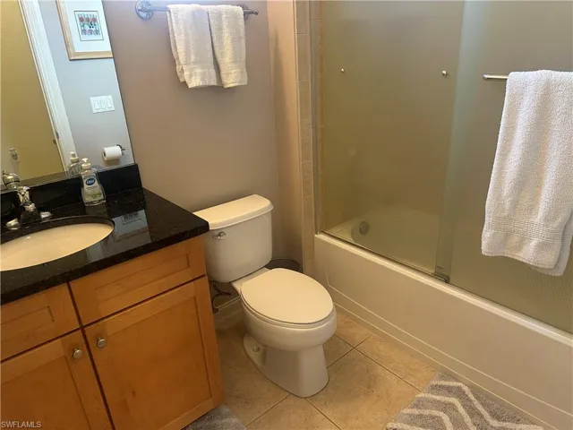 Full bathroom featuring vanity, bath / shower combo with glass door, and light tile patterned flooring