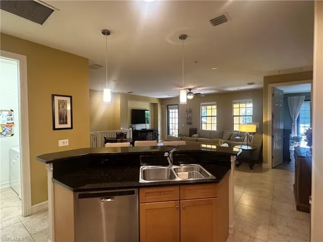 Kitchen featuring dishwasher, a kitchen island with sink, open floor plan, hanging light fixtures, and light tile patterned floors