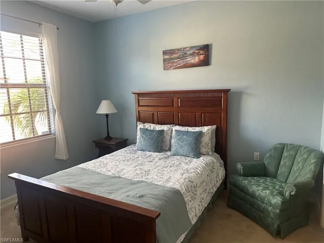 Carpeted bedroom featuring a textured wall and ceiling fan