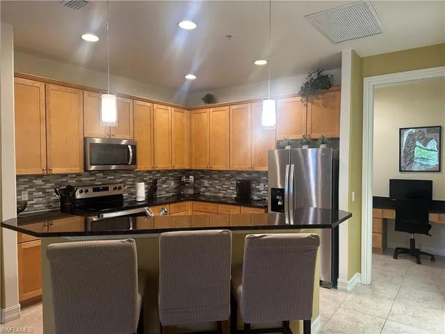 Kitchen featuring, a breakfast bar, stainless steel appliances, recessed lighting, and decorative backsplash