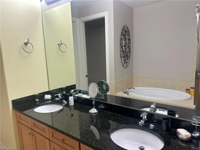 Full bath featuring double vanity and a bath
