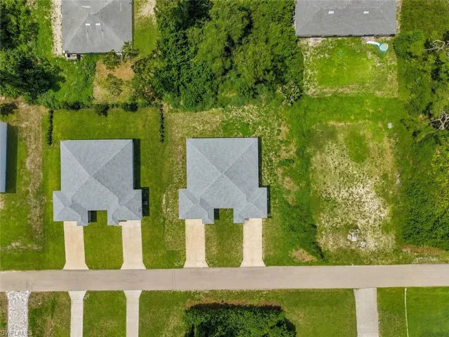 Aerial perspective showcasing two properties with light grey shingled roofs and individual concrete driveways