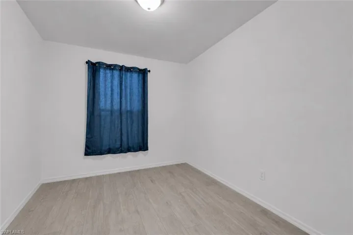Interior room featuring light wood-finish flooring, white walls, and a ceiling-mounted light fixture