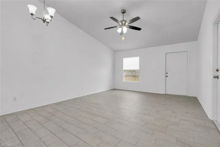 Spacious room featuring vaulted ceilings, light-toned wood-finish flooring, and a modern ceiling fan with integrated lighting