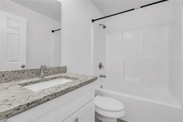 Bathroom featuring a white vanity with a light granite countertop, an undermount sink, and brushed nickel fixtures