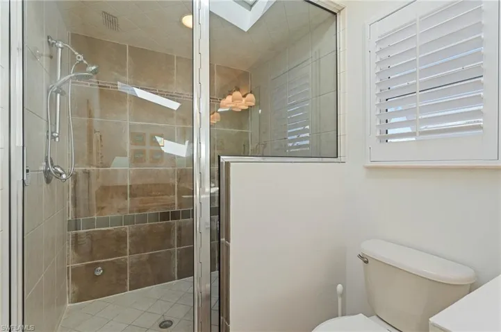 Bathroom with a skylight, walk in shower, and toilet