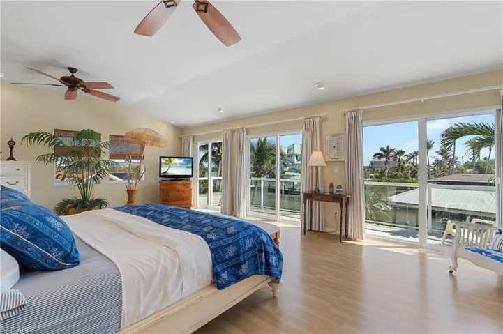 Bedroom featuring vaulted ceiling, ceiling fan, access to exterior, and light wood look tile floors