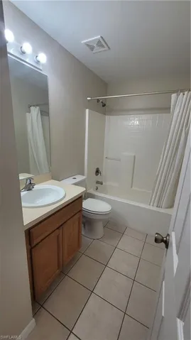 Full bathroom featuring shower / tub combo with curtain, vanity, and light tile patterned floors