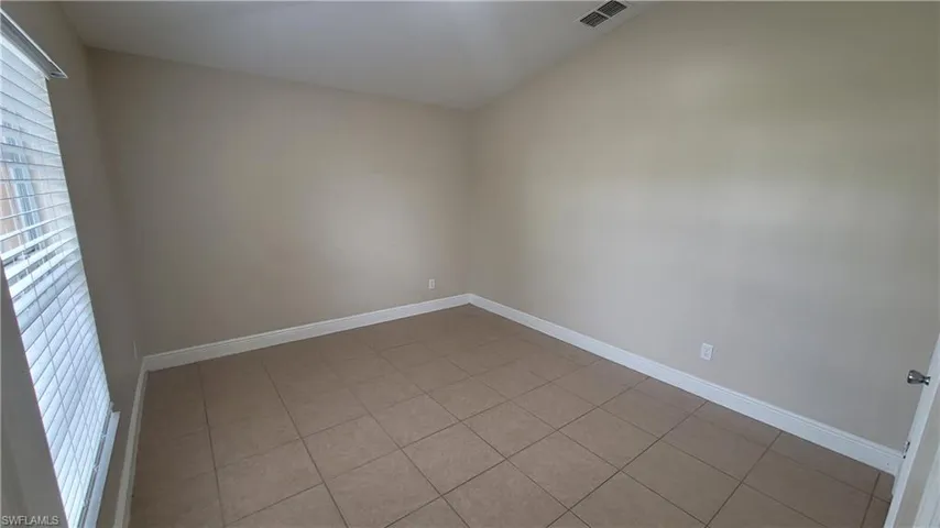 Unfurnished room with light tile patterned floors and vaulted ceiling