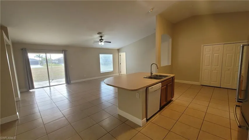 Kitchen featuring light countertops, a ceiling fan, lofted ceiling, open floor plan, and freestanding refrigerator