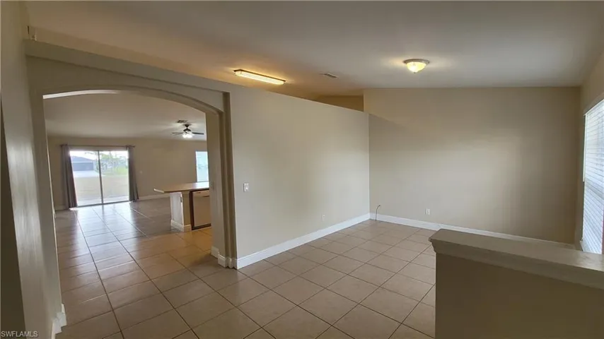 Unfurnished room featuring arched walkways and light tile patterned floors