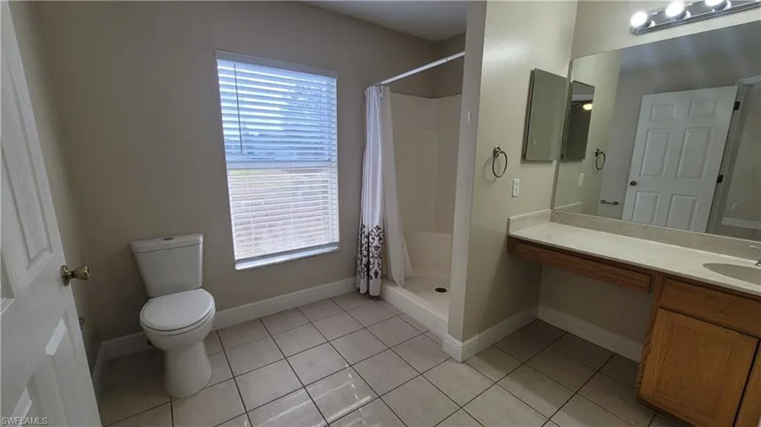 Full bath featuring a shower stall, vanity, and light tile patterned floors