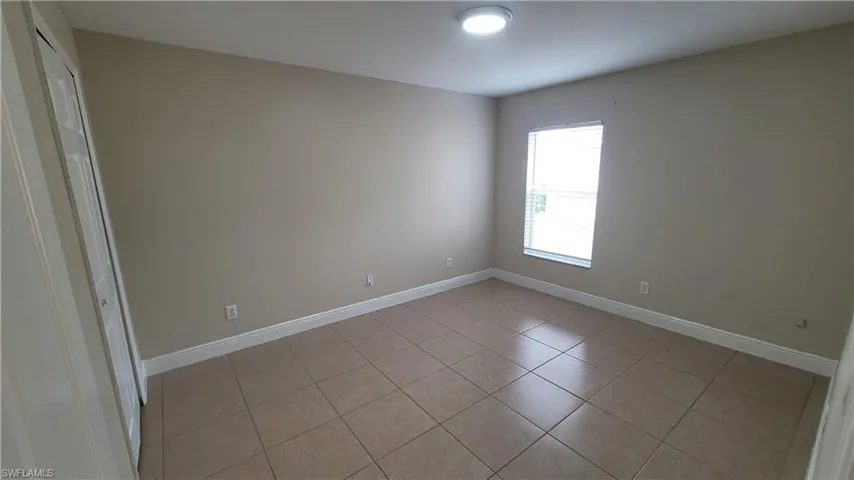 Unfurnished room featuring light tile patterned flooring and baseboards