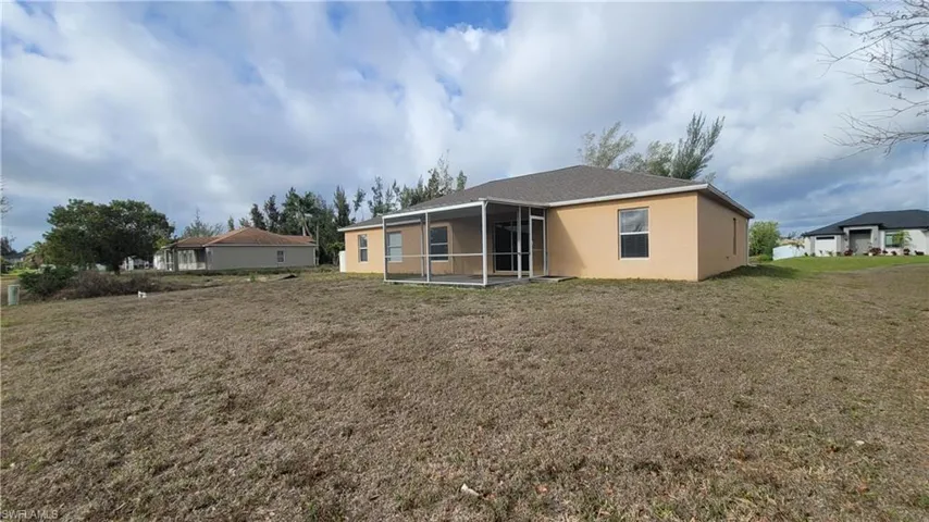 Back of property with a sunroom, stucco siding, and a yard
