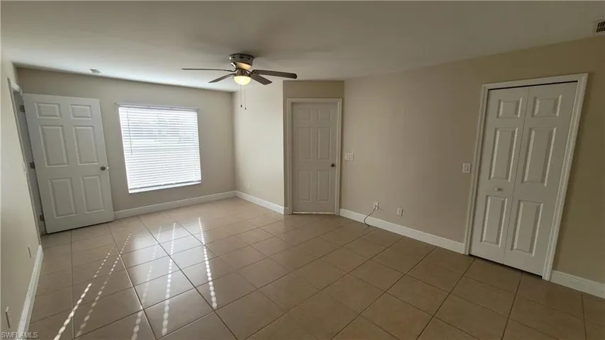 Unfurnished bedroom featuring light tile patterned flooring, ceiling fan, and a closet