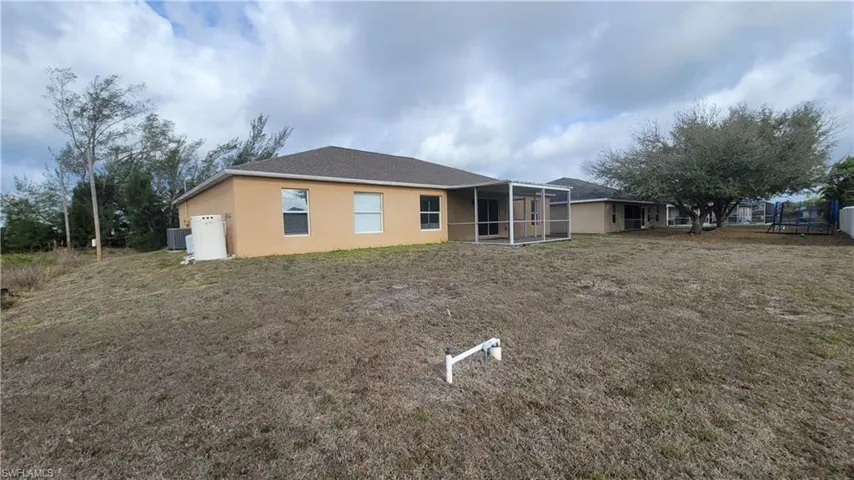 Back of property featuring a sunroom, stucco siding, a yard, and a trampoline