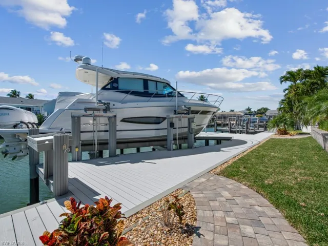 View of dock with boat lift and a yard