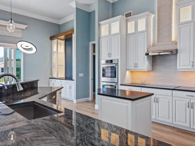 Kitchen featuring crown molding, a sink, wall chimney exhaust hood, light wood-type flooring, and black electric cooktop