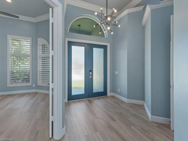 Foyer entrance with baseboards, crown molding, wood finished floors, and french doors
