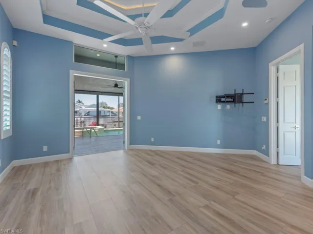 Unfurnished room featuring recessed lighting, baseboards, a raised ceiling, ceiling fan, and wood finished floors