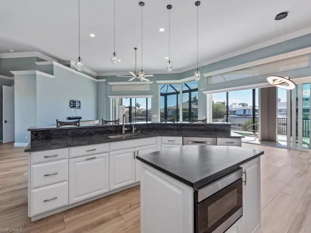 Kitchen with ornamental molding, stainless steel microwave, a sink, open floor plan, and a center island