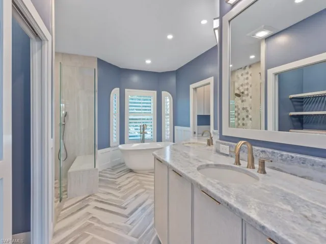 Bathroom with double vanity, a sink, a soaking tub, and walk in shower