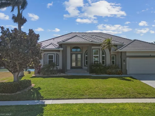 View of front facade featuring driveway, french doors, stucco siding, a tiled roof, and a garage