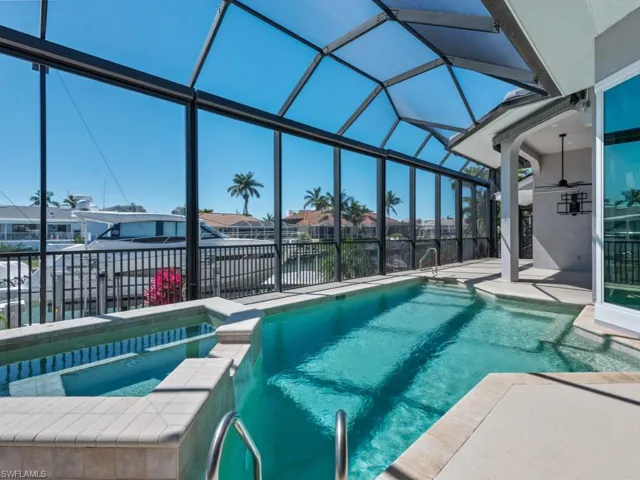 View of pool featuring a residential view, a pool with connected hot tub, glass enclosure, and a patio