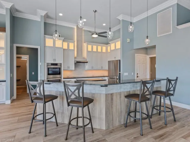 Kitchen featuring a ceiling fan, stainless steel appliances, a breakfast bar area, and crown molding