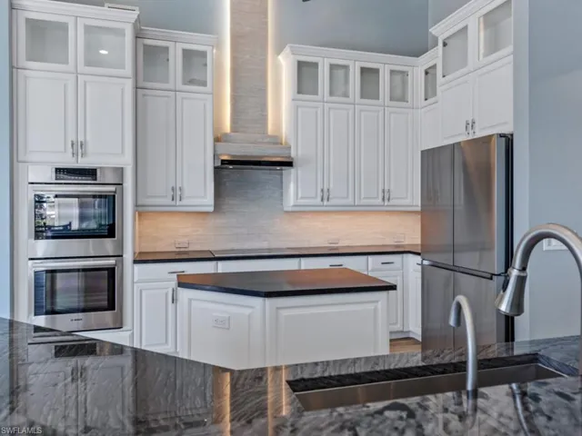 Kitchen featuring backsplash, white cabinets, and appliances with stainless steel finishes