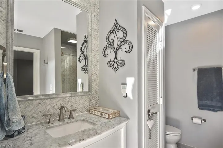 Bathroom featuring vanity, toilet, and backsplash