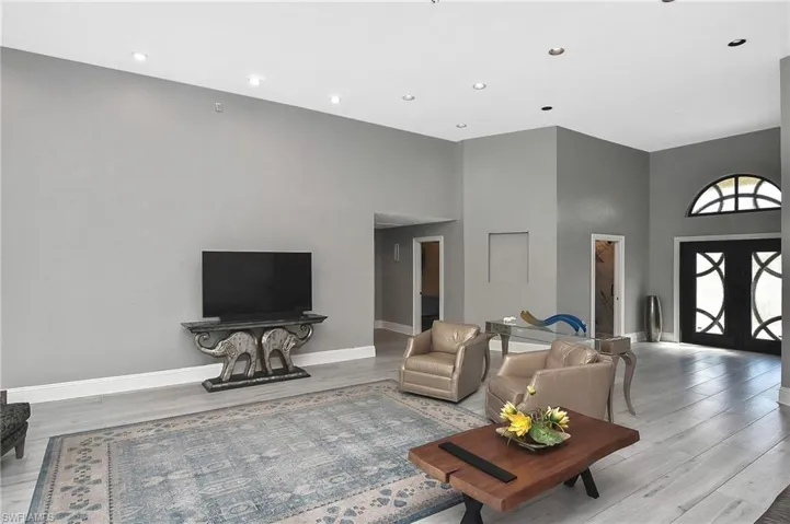 Living room with light hardwood / wood-style flooring and a high ceiling