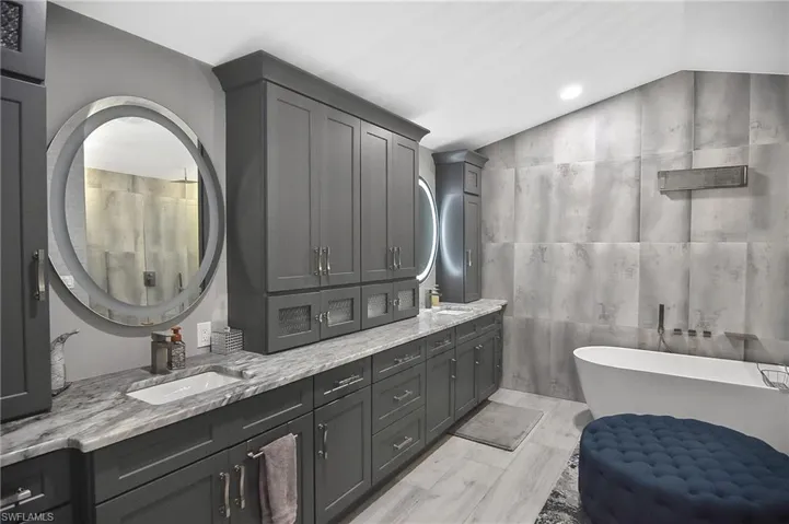 Bathroom with hardwood / wood-style flooring, a tub to relax in, double sink vanity, and tile walls