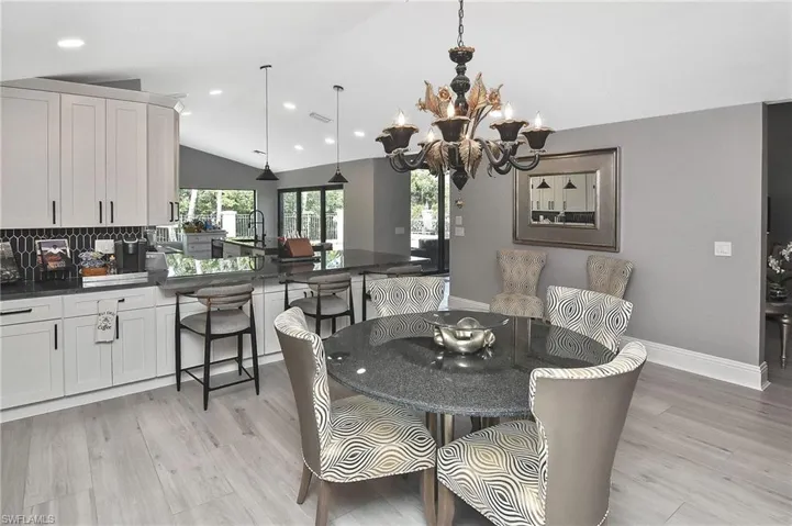 Dining space with vaulted ceiling, light wood-type flooring, and an inviting chandelier