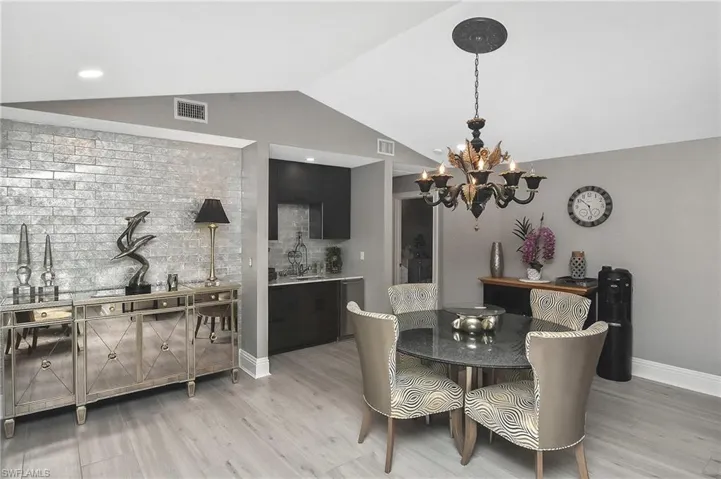 Dining space featuring light hardwood / wood-style flooring, an inviting chandelier, and lofted ceiling