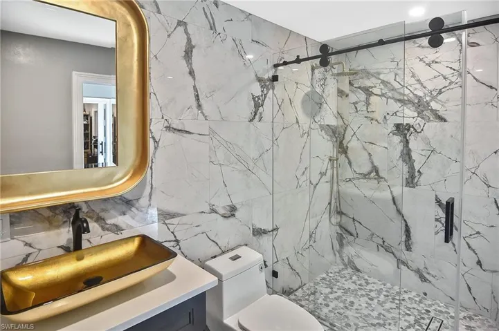 Bathroom featuring tile walls, toilet, vanity, and an enclosed shower