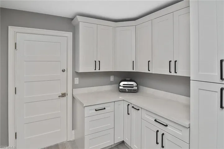 Kitchen with white cabinets, light hardwood / wood-style floors, and refrigerator