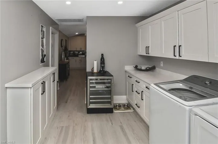 Laundry area featuring separate washer and dryer, light hardwood / wood-style floors, and beverage cooler
