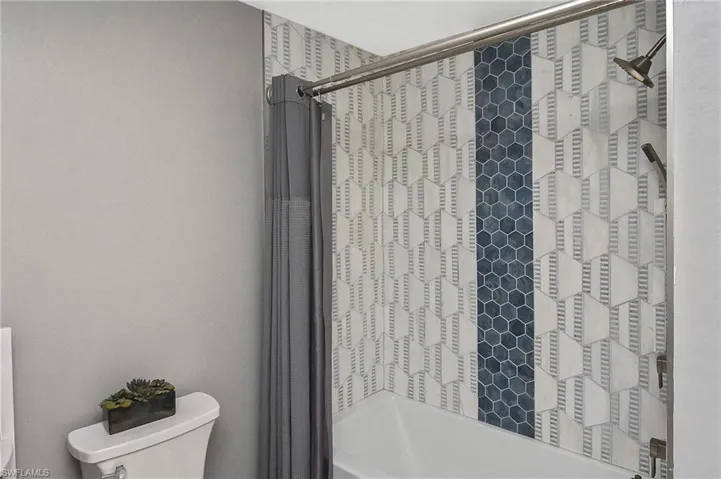 Bathroom featuring tiled shower / bath combo and toilet