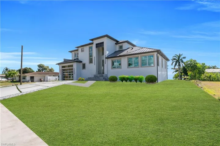 View of front of house featuring a front yard, stucco siding, a garage, and driveway