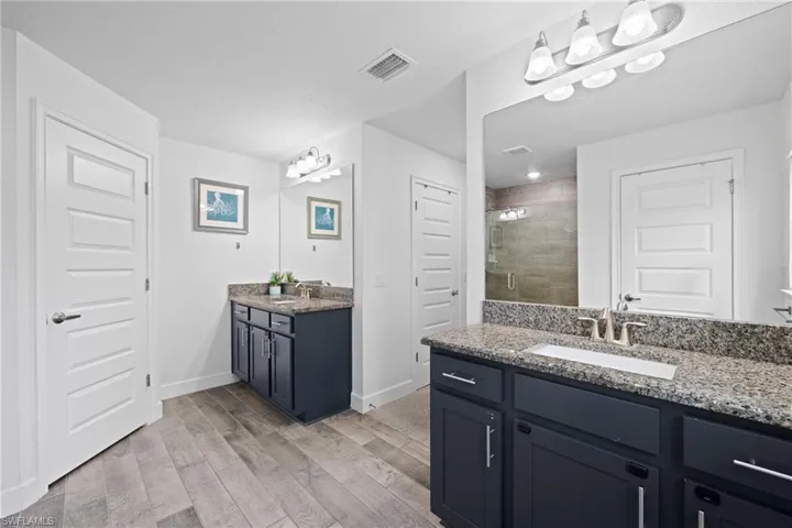 Bathroom with two vanities, light wood-type flooring, and a stall shower