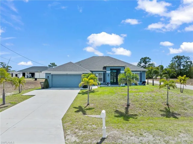 Single story home featuring roof with shingles, a front lawn, an attached garage, and driveway