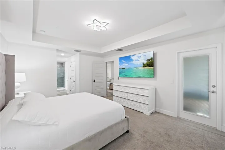 Bedroom featuring a raised ceiling and light colored carpet